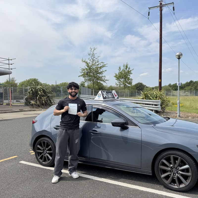 An Xclusive Driving student holding their practical test pass certificate beside the tuition car