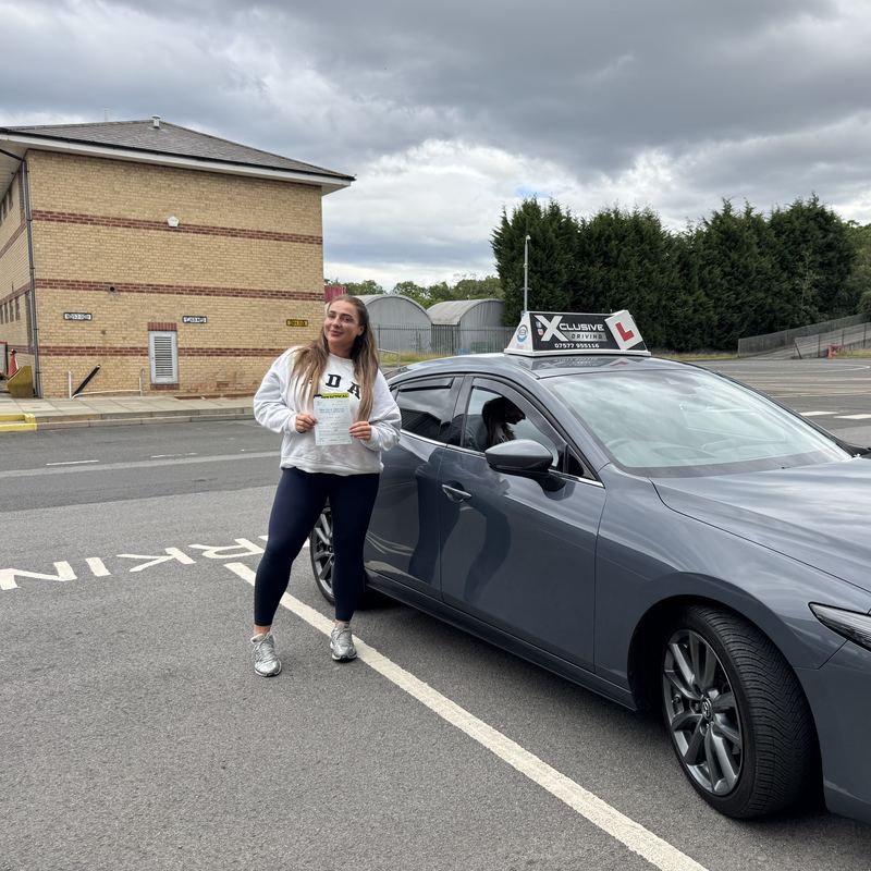 A newly qualified driver with their DVSA pass certificate outside the driving test centre